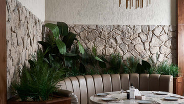 modern sofa infront of green plants and atone wall in the background , stacked stone veneers
